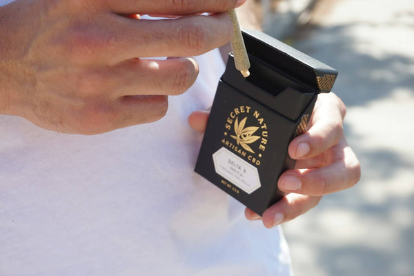 Man removing a pre roll from premium CBD packaging