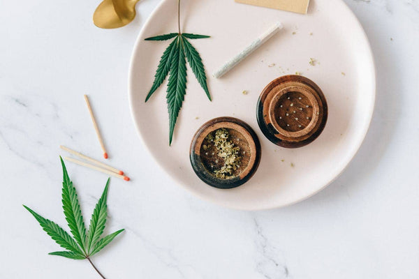 Cannabis, grinder, and weed cigarette on a plate